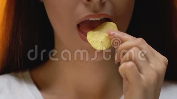 年轻女士吃辛辣的薯片不健康的零食和快餐关门视频的预览图