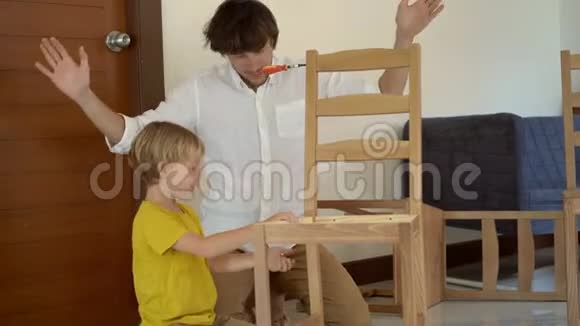 父子俩在组装小零件的木制家具时玩得很开心小男孩帮助他父亲组装一个视频的预览图