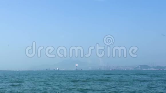 船漂浮在蓝色的海洋上的汽车桥和城市景观背景在海上游泳的商船和船只山区视频的预览图