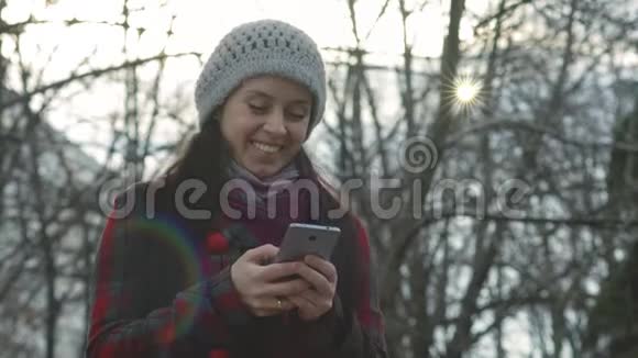 年轻开朗的女人在户外散步时看有趣的视频或用手机发短信视频的预览图