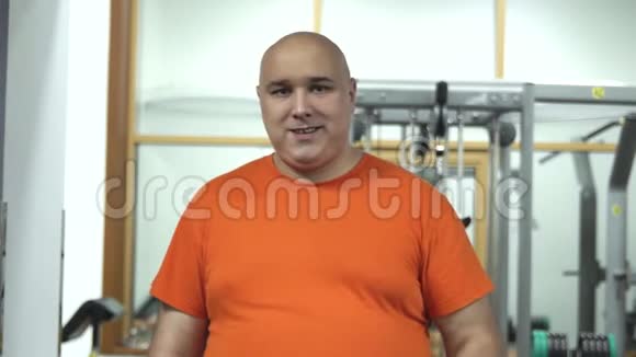 胖帅哥穿着橙色T恤抱着韭菜激励着做运动视频的预览图