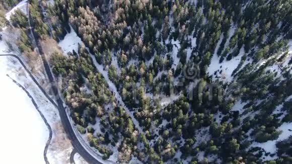 在长长的道路和覆盖着4k积雪的巨大森林上的俯视图视频的预览图