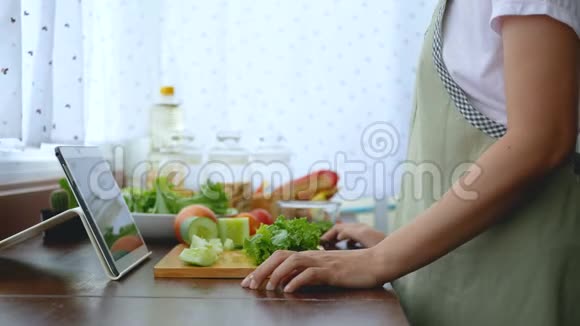 4K女人用手指在平板电脑上滑动切鲜生菜准备烹饪原料然后在网上烹饪视频视频的预览图