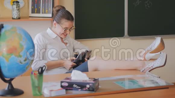 年轻女子老师坐在教室里玩手机游戏老师写短信慢动作视频的预览图