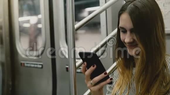 快乐迷人的千禧自由职业者女孩坐在地铁列车上使用社交网络智能手机应用程序和微笑视频的预览图