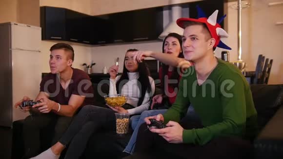 四个年轻人在一起玩得很开心两个年轻人在玩游戏而他们的女朋友在谈论游戏视频的预览图