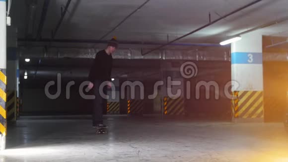 地下停车场一个年轻人在玩滑板展示简单的技巧视频的预览图