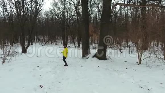 冬季森林中带绳跳绳的黄衣长胡子运动员视频的预览图