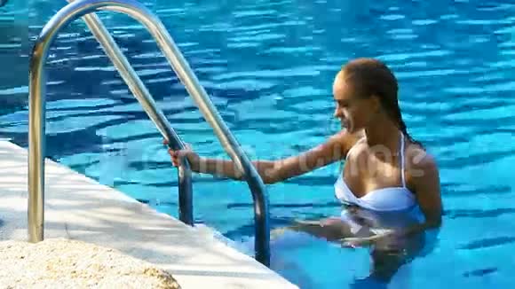 女人爬上游泳池的梯子视频的预览图