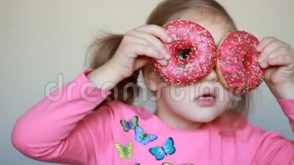 孩子和甜甜圈特写小女孩吃甜甜圈加糖美味的甜的甜的视频的预览图