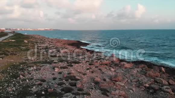 空中无人驾驶飞机观看美丽的岩石海岸绿色的行人旅游路径和巨大的海浪视频的预览图