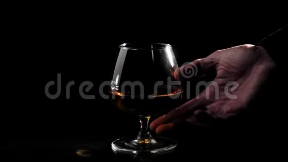 豪华白兰地黑桌上黑色背景的金色干邑玻璃手拿杯子喝白兰地白兰地视频的预览图