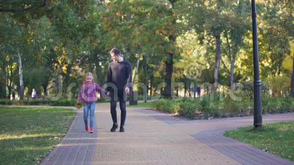 带着一束秋叶的父女放学后一起散步视频的预览图