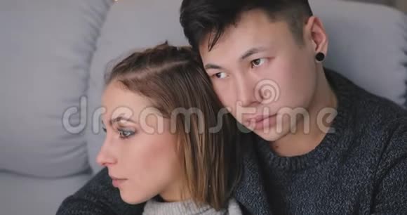 悲伤的年轻夫妇坐在沙发上拥抱视频的预览图