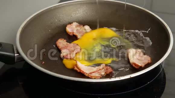 快关门两个鸡蛋被炸成一个热煎锅里面有煎培根早餐和厨房概念视频的预览图