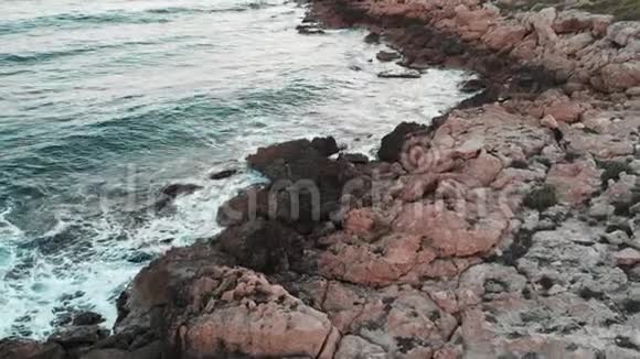 关闭大石头的无人机视图空中近距离拍摄蓝色海浪撞击岩石海滩视频的预览图