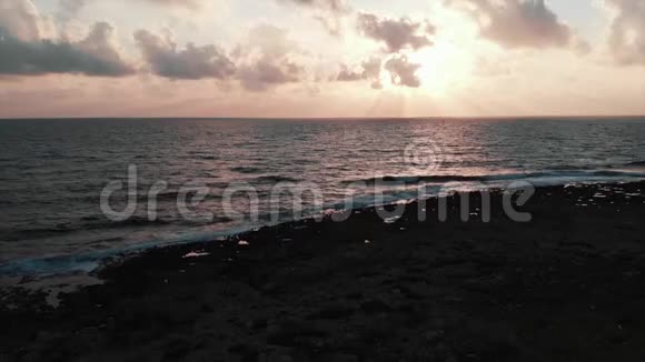 鸟瞰美丽的粉红色日落大海浪冲击岩石海滩风暴视频的预览图