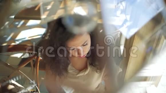 一个卷发的女人坐在一家咖啡馆的窗户附近从报纸上看到树叶上文视视频的预览图