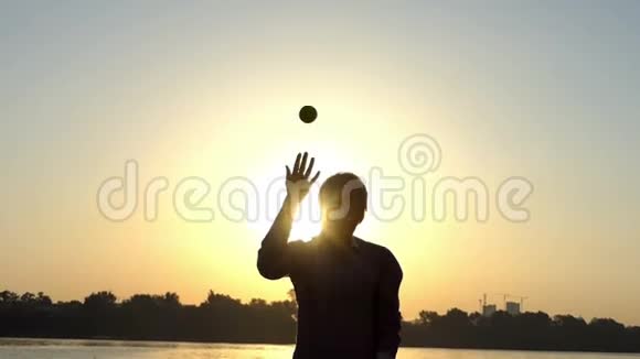 夏天日落时分一个吝啬鬼在河岸上扔一个球视频的预览图