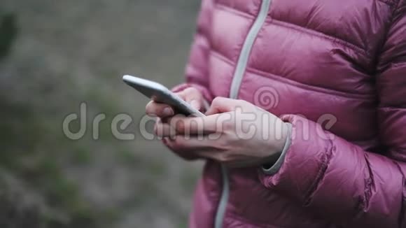 手拿着粉红色夹克手拿着手机视频的预览图