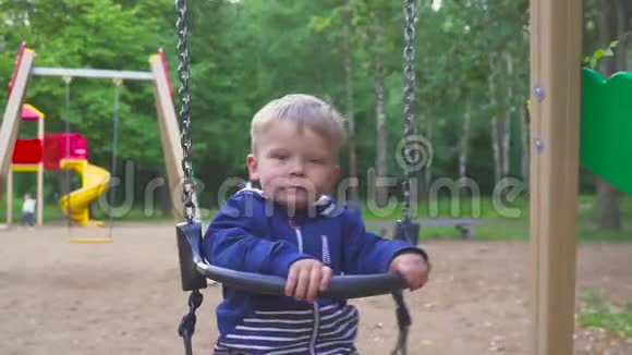 两岁的男孩正在公园里骑秋千视频的预览图