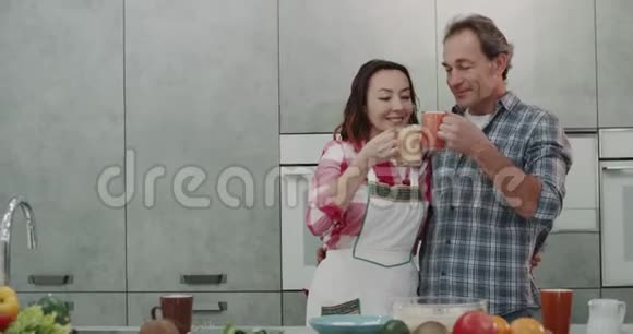 成熟的夫妻在早上喝新鲜的冰沙作为早餐非常有魅力美丽的现代厨房设计视频的预览图