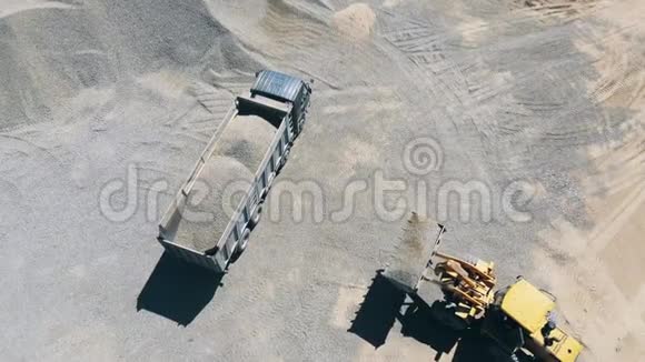 黄色拖拉机装载一辆带有碎石的卡车视频的预览图