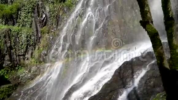 在绿色岩石背景下的瀑布中彩虹视频的预览图