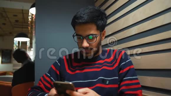特写镜头印度小伙在咖啡厅与智能手机交流视频的预览图