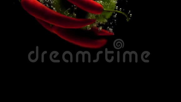 红辣椒和绿皮红辣椒在黑色的背景下落入水中视频的预览图
