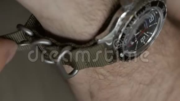 身着卡其布衣服的男子的手戴在潜水员的手腕上尼龙带上的手表视频的预览图