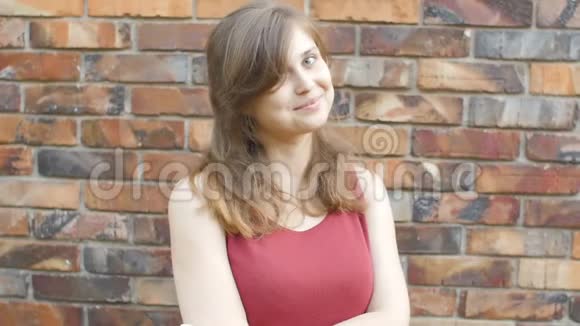 年轻可爱的美丽女孩在红砖墙的背景下微笑和调情梦幻浪漫的女人对面的石头文字视频的预览图