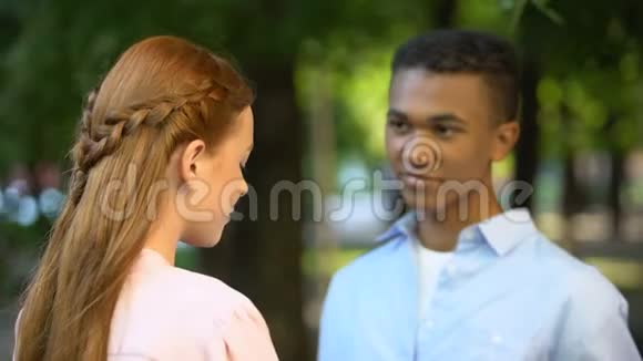 害羞的美国黑人男孩向公园里微笑的女孩献上鲜花视频的预览图
