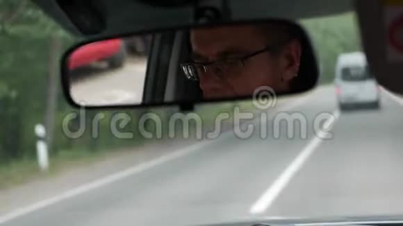 老人在乡间路开车汽车后视镜中的面部反射特写镜头4k视频的预览图