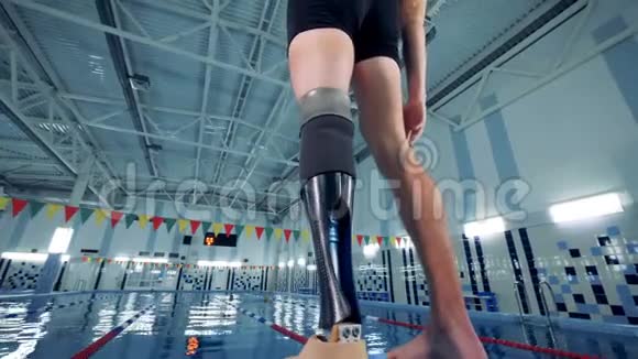 一位残疾游泳运动员在泳池旁热身后景视频的预览图