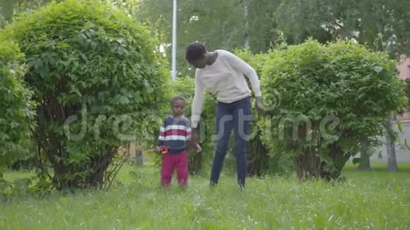 漂亮的非裔美国女人和她的小儿子牵着手在公园里散步可爱的孩子花时间视频的预览图