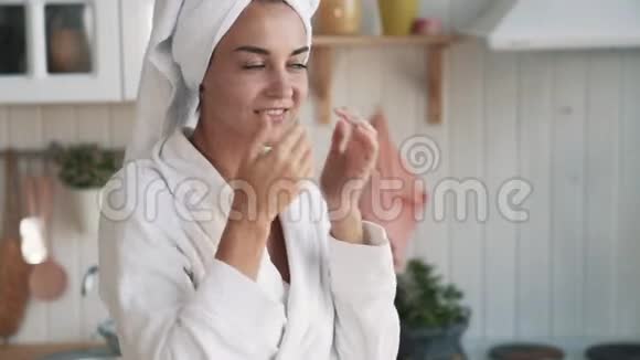 贴身穿浴袍的女孩头上有毛巾脸上涂着奶油动作缓慢视频的预览图