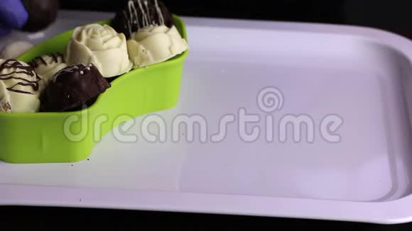 一个戴着橡胶手套的人把巧克力从托盘里放进容器里黑色和白色巧克力中的釉糖国际视频的预览图