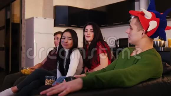四个年轻人在看电视年轻女子试图把电视遥控器从那家伙身上拿走视频的预览图