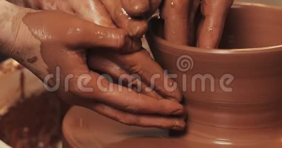一对夫妇的手在陶工的轮子上形成一壶粘土女性的手帮助男人手塑造粘土的形状快关门视频的预览图