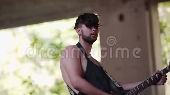 酷吉他手在一个废弃工厂的地盘上穿着工作围裙弹吉他视频的预览图