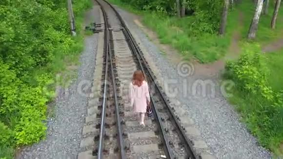 一个走在铁轨上的年轻女孩在公园里远足视频的预览图