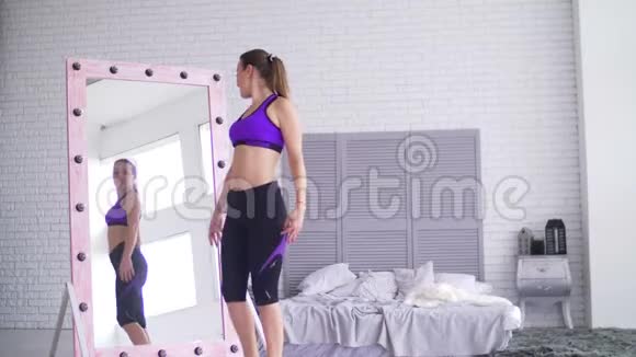 运动的女人在镜子里欣赏她的体形视频的预览图