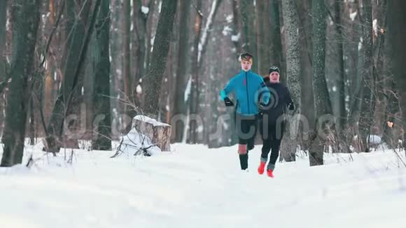 穿着运动服装的男女青年在冬季森林中奔跑视频的预览图