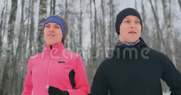 一个漂亮的女人和一个男人在森林里奔跑在冬天适当的营养和健康的生活方式慢动作视频的预览图