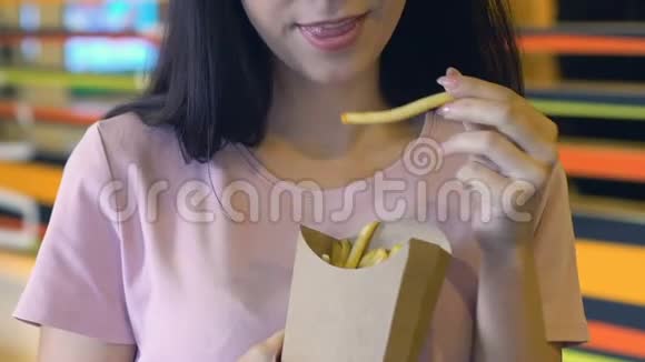 快乐的女人在镜头前吃脆脆和咸炸薯条外卖视频的预览图