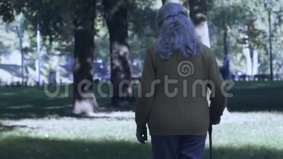 老年妇女在公园里用棍子走路老年时腿有问题关节疼痛视频的预览图