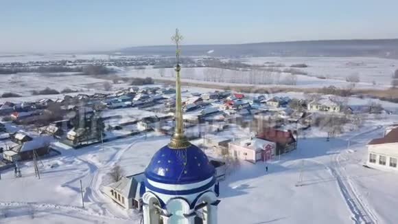 在晴朗的冬天在小村庄附近的俄罗斯东正教教堂的蓝色穹顶和金色十字架的近景视频的预览图