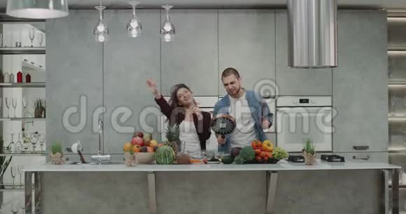 厨房里有趣的有魅力的一对夫妇准备食物同时跳舞一起玩疯狂的时光视频的预览图
