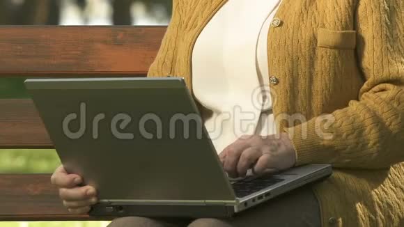 微笑着的退休女士慢慢地打字在外面休息浏览互联网视频的预览图
